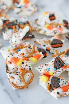 halloween pretzels and candy bars are arranged on a white marble surface with sprinkles