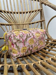 a pink and yellow flowered bag sitting on top of a wooden chair