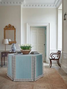 a room with a table, mirror and vase on the floor next to a chair