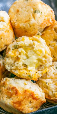 some biscuits are piled on top of each other in a blue bowl with broccoli and cheese