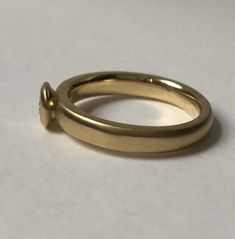 a close up of a gold ring on a white surface with the top part missing