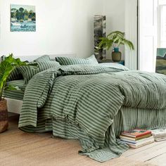 a bed with green and white striped comforter in a room next to a window