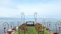 an outdoor ceremony set up with chairs and flowers on the grass by the water's edge