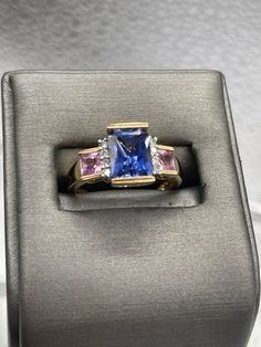 A beautiful ladies multi-gemstone ring designed and made in 10 karat solid yellow gold.  Set with a 2.5 carat rectangular cut Tanzanite stone bordered on each side with four fine white round Diamonds and two princess cut Pink Topaz set one on each side. This is an unusual composition of colored stones that always looks amazing and drips with sparkle. Weight:  4.2 grams Size:  7 ½  Please See Our Video Remember - If you're purchasing for yourself or a gift for a loved one, buy with confidence.  W Rectangular Sapphire Ring With Accent Stones, Rectangular Sapphire Ring For Anniversary, Formal Square Cut Sapphire Ring With Accent Stones, Rectangular Sapphire Anniversary Ring, Rectangular Sapphire Ring With Accent Stones For Formal Occasions, Anniversary Multi-stone Emerald Cut Diamond Ring, Emerald-cut Sapphire Ring With Gemstone Accents, Emerald Cut Sapphire Ring With Gemstone Accents, Rectangular Sapphire Ring With Prong Setting