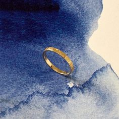 a gold wedding ring on top of a blue watercolor background