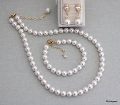 a white pearl necklace and earring set in a gift box on a gray background