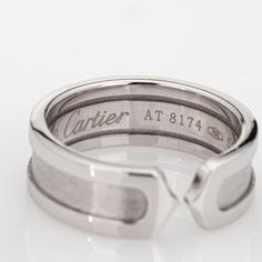 This is part of Chairish’s Fine Jewelry assortment.  Vintage Cartier Double C logo ring crafted in 18 karat white gold (circa 2000).    The out of production Cartier ring features a high polish outer bands with an inset satin finish. The ring is great worn alone or stacked with your fine jewelry from any era.  The ring is in very good condition and was recently lightly cleaned and polished. No box or papers.  Particulars:  Weight: 7.6 grams  Stones:  N/A  Size & Measurements: The ring is a size Luxury Silver Engraved Ring For Formal Occasion, Modernist Open Band Rings For Formal Occasions, Designer White Gold Promise Ring, Designer Hallmarked White Gold Rings, Designer White Gold Rings Hallmarked, Designer White Gold Hallmarked Rings, Modern Cartier Ring Jewelry, Modernist Hallmarked Wedding Rings, Designer White Gold Rings For Formal Events