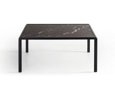 a black table with a marble top and metal legs, against a white background that has only one leg visible