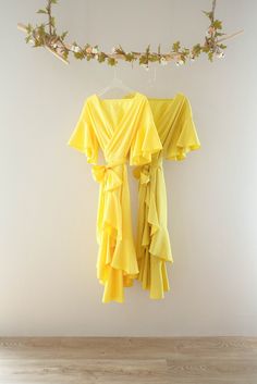 a yellow dress hanging on the wall next to a branch with leaves and branches in it