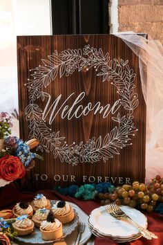 a wooden sign sitting on top of a table next to plates and cups filled with food