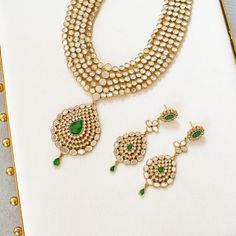 An heirloom of divinity, crafted through the ages! Introducing an opulent fiver-layer kundan mala, adorned with a magnificent emerald stone centerpiece that exudes timeless elegance, this set blends the regal charm of kundan with the vibrant allure of emeralds. A masterpiece of craftsmanship, it promises to elevate any occasion with its majestic allure. The listing includes long mala and a pair of matching earrings. Gold-plated on high-quality brass as base metal. Made by order. Kindly allow 5-7 Emerald Kundan Necklace With Intricate Design For Festive Occasions, Elegant Gold Kundan Necklace For Rituals, Festive Emerald Kundan Necklace With Intricate Design, Elegant Kundan Necklace With Emerald Stone Work, Elegant Kundan Emerald Necklace For Festive Occasions, Elegant Emerald Kundan Necklace With Stone Work, Elegant Emerald Kundan Necklace For Festive Occasions, Festive Emerald Kundan Chandbali Necklace, Festive Chandbali Kundan Necklace With Emerald