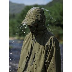 a person wearing a raincoat and standing in the water splashing from his face