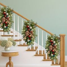 christmas wreaths on the banister and stairs decorated with garland, baubies and bows