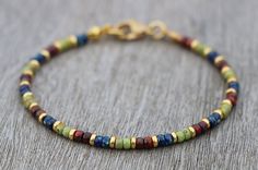 Friendship bracelet, colorful beaded with tiny Miyuki seed beads in beautiful red, green and blue. These glass beads have a picasso coating; each bead is unique! The gold colored spacers make the colors stand out even more! It also ensures a dainty touch. You can wear this thin bohemian bracelet on its own, for a minimalist look, or you can stack it with other boho bracelets. It will give a beautiful multi color accent to your outfit. Great for those special moments, or spoil yourself and make i Simple Bracelets Diy Beads, Seed Bead Color Combinations, Bead Bracelets Ideas, Bracelet Homemade, Tiny Bead Bracelet, Homemade Bracelets, Stone Bead Jewelry, Colorful Bracelet, Miyuki Bracelet