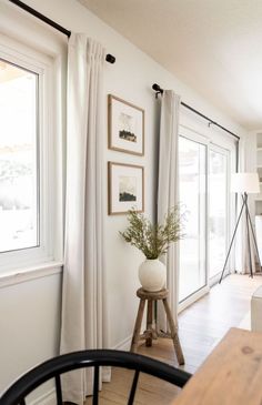 a living room filled with furniture and a wooden table next to a window covered in white curtains