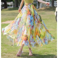 a woman in a yellow top and multicolored skirt is dancing on the grass