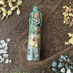 a bottle filled with rocks and flowers sitting on top of a wooden table next to other items