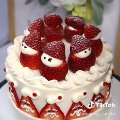 a cake with strawberries on top and white frosting, sitting on a table