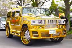 a yellow hummer truck is driving down the street in front of other cars and trees