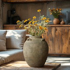 a large vase with yellow flowers in it sitting on a table next to a couch