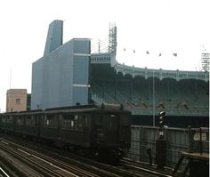 a train on the tracks in front of a stadium