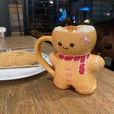 there is a small ceramic bear sitting next to a cookie on the table in front of it