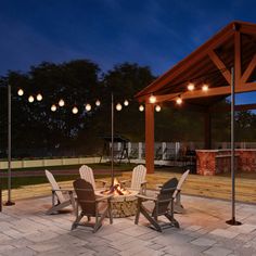 an outdoor fire pit surrounded by chairs and lights