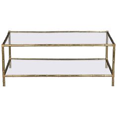 a gold metal and glass coffee table with two shelves on each side, against a white background