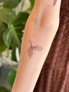 a woman's arm with a tattoo on it and leaves around the wrist area