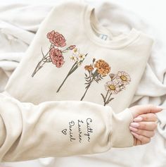 Introducing our adorable Cute Mama Sweatshirt, a perfect and unique gift for mom! This cozy and stylish sweatshirt not only showcases your love for motherhood but also allows you to personalize it with customized children names on the sleeve.  Surprise and delight mom with this special sweatshirt, a perfect gift for Christmas or any occasion. Crafted with love and attention to detail, this sweatshirt is not only fashionable but also incredibly comfortable.  Treat yourself or surprise your mother-in-law with this heartfelt and thoughtful gift that will surely warm her heart. Shop now and make every mom feel extra special with our customized Cute Mama Sweatshirt! Due to the custom nature of the product, the FLOWER & Name SIZE VARIES WITH EACH CUSTOM ORDER AND MAY NOT BE SIZE AS APPEARS IN SA Grandmother Christmas Gift, Gifts For Mother In Law, Sentimental Gifts For Mom, Children Names, Gift For Grandmother, Flower Sweatshirt, Mother Shirts, Unique Gifts For Mom, Thoughtful Christmas Gifts