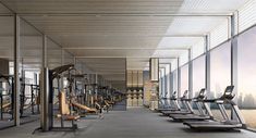 an empty gym with treadmills and windows overlooking the water in front of it