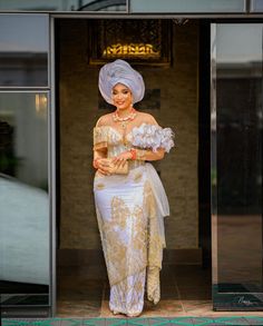 a woman in a white and gold dress is standing at the entrance to a building