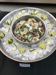 a bowl filled with food on top of ice covered in limes and sliced onions