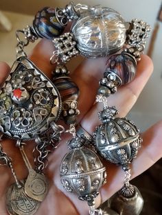 An assemblage of Yemen wedding globe beads, one is hallmarked, and a pear shaped fibula pendant from Siouan Ouan region in Morocco. These are rare hard to find silver pendants. The central stone I think is not real coral. It has three original silver and niello charm pendants on original chains, one was missing, so I've added a Berber silver evil eye charm. Handmade chain using sterling wire with Yemen berry beads, (silver content unknown), faceted pyrite, silver beads from India, silver plated Unique Ceremonial Jewelry With Silver Beads, Unique Antique Silver Jewelry With Silver Beads, Unique Silver Beads Pendant Jewelry, Unique Silver Beaded Pendant Jewelry, Spiritual Decorative Silver Jewelry, Unique Silver Round Beaded Jewelry, Spiritual Silver Decorative Jewelry, Unique Sterling Silver Jewelry With Polished Beads, One-of-a-kind Silver Jewelry For Festivals