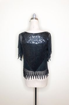 This is a stunning silk beaded top by Swee Lo, from Neiman Marcus. The beaded portion is a sheer overlay with a tank attached. Top is covered in black sequins and bugle beads. The hemline and sleeve detail add interest to the blouse. We are loving these beaded tops with white denim for spring and summer. 100 percent silk. Size tag S. Check measurements carefully, no stretch. Measurements taken with top laying flat and doubled where appropriate. In order to determine fit we recommend comparing me Sheer Silk Party Tops, Glamorous Embellished Short Sleeve Blouse, Glamorous Short Sleeve Embellished Blouse, Sheer Silk Tops For Night Out, Sheer Short Sleeve Mesh Top For Party, Elegant Sheer Tops For Party Season, Elegant Short Sleeve Mesh Top For Evening, Fitted Sequin Mesh Top For Summer, Elegant Fitted Sequin Mesh Top