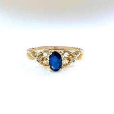 a gold ring with an oval blue stone and two small white diamonds on the side