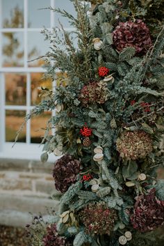 a tall christmas tree with red berries and greenery