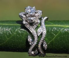 a close up view of a wedding ring on a green leafy surface with diamonds