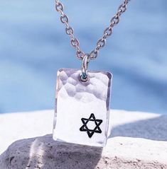 This necklace is sure to become a valued part of your own Judaica jewelry collection because of its unique combination of current elegance and traditional faith. Any friend of Israel and the symbols represented by this star would like to receive this necklace as a holiday gift! ➤FEATURES Pendant - 7/8'' x 5/8'' Choose chain ➤CHOOSE CHAIN 1. Dark metal - rolo chain - 2.4mm 2. Ball chain stainless steel - 2.4mm 3. Regular stainless steel chain - larger links  4. Regular stainless steel chain - smaller links 5. Ball chain - dainty ➤CHAIN LENGTHS Ball chains are 24 inches and can be shortened by snipping with scissors. Regular chains are 20 inches and can be ordered in other lengths.  Dark rolo chain is 20 inches ➤CRAFTSMANSHIP Everything Beautiful designs jewelry using only the highest qualit Silver Necklace For Men, Judaica Jewelry, Judaica Gifts, Dark Metal, Jewish Jewelry, Mens Silver Necklace, Hanukkah Gifts, Hammered Sterling Silver, Necklace For Men