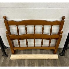 a wooden bed frame sitting on top of a hard wood floor next to a brick wall