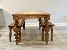 a wooden table and two benches in a room with white walls, hardwood floors and tile flooring