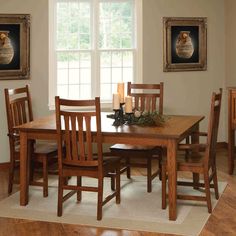 a dining room table and chairs in front of a window with two framed pictures on the wall