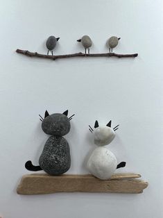 two cats sitting on top of a wooden shelf next to birds perched on the branch