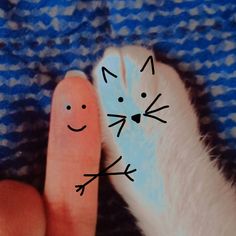 a finger with a cat drawn on it next to a person's thumb and hand