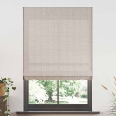 a living room with white walls and a window covered in beige roman blind shades, next to a fireplace