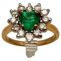 This stunning cocktail ring features a beautiful heart-shaped natural emerald, surrounded by 12 prong-set diamonds. The band is crafted from 14k yellow gold and the ring is a size 6.25. The heart-shaped emerald measures approx. 6mm x 6.5mm and the diamonds add the perfect amount of sparkle to this gorgeous piece. This ring is perfect for anyone who loves unique and high-quality jewelry that will stand out in any crowd. EMERALD Through time, the emerald has been known as a symbol of truth and lov Diamond Cocktail Rings, Beautiful Heart, Natural Emerald, High Quality Jewelry, Cocktail Rings, Prong Setting, Heart Ring, Emerald, Ring