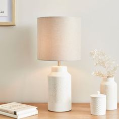 two white vases and a lamp on a table