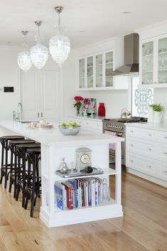 a white kitchen with an island and lots of counter space in front of the sink