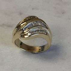 A stunning 14kt Yellow Gold Lady's Cubic Zirconia Baguette Channel Set Band with 1.50ct approx. total weight of all channel set straight baguette Cubic Zirconia (CZ) stones in finger size 7. This ring can be resized for an additional $95.00 upon request. The ring weighs 7.25 grams. Excellent band as a Wedding/Anniversary Gift. This item would Retail for $1,279.00 Classic Gold Baguette Diamond Ring, Formal Baguette Diamond Jewelry, Yellow Gold Baguette Jewelry With Channel Set, Diamond Baguette Jewelry With Prong Setting, Channel Set Baguette Rings For Anniversary, Baguette Diamond Marquise Cut Jewelry, Baguette Diamond Jewelry With Prong Setting, Baguette Channel Set Rings For Anniversary, Dazzling Gold Diamond Ring With Baguette Diamonds