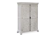 a white cabinet with carvings on the front and bottom doors, sitting against a white background